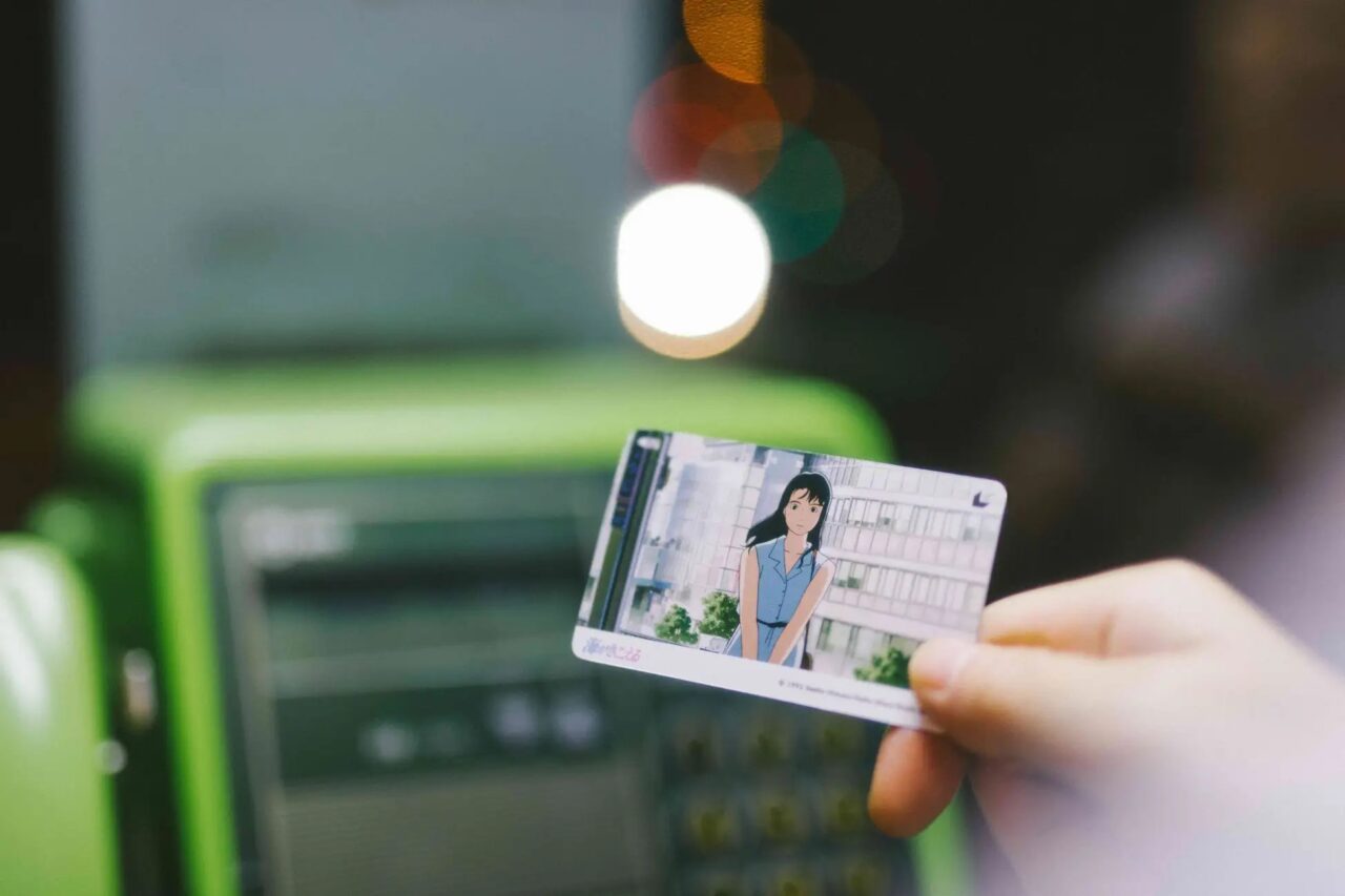 テレホンカード風ムビチケを公衆電話でかざしている写真です