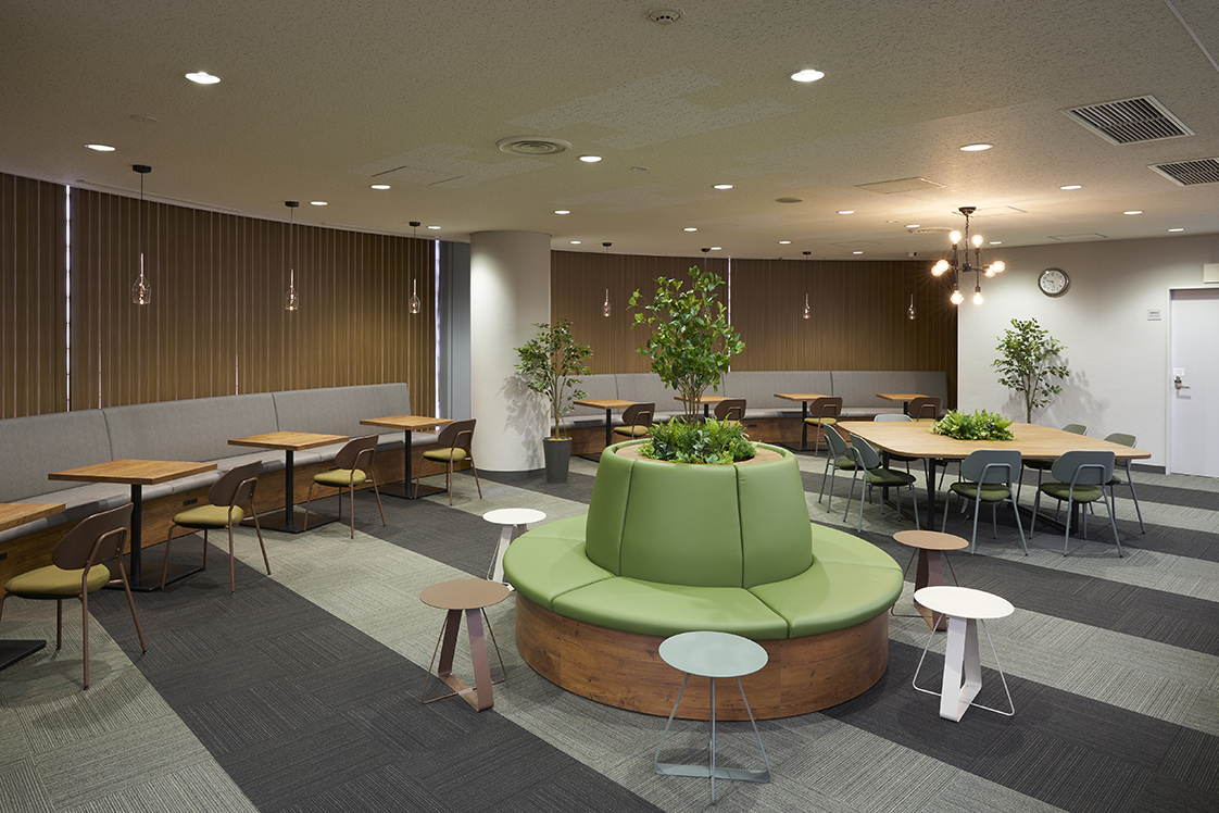 落ち着いた照明とグリーンが配置された亜細亜大学図書館のリニューアルフロア キャプション
