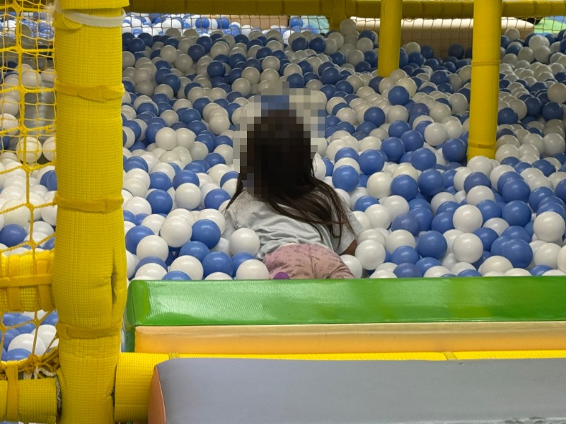 ボールプールの中で体をうずめて楽しむ子どもの様子
