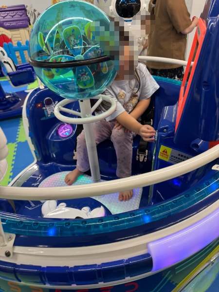 宇宙船を模したライド型アトラクション遊具に乗って楽しむ様子