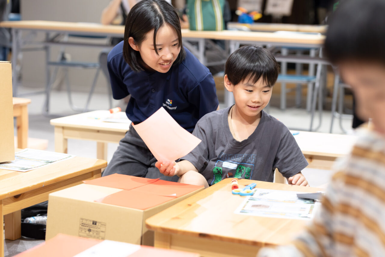 講師と一緒にダンボールや色紙を使ってブロック制作に取り組む子ども