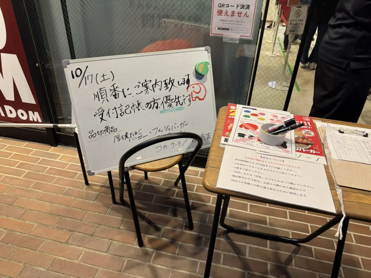 「順番にご案内致します」と書かれた店頭の受付記帳ボードと椅子。品切商品の案内も手書きされている
