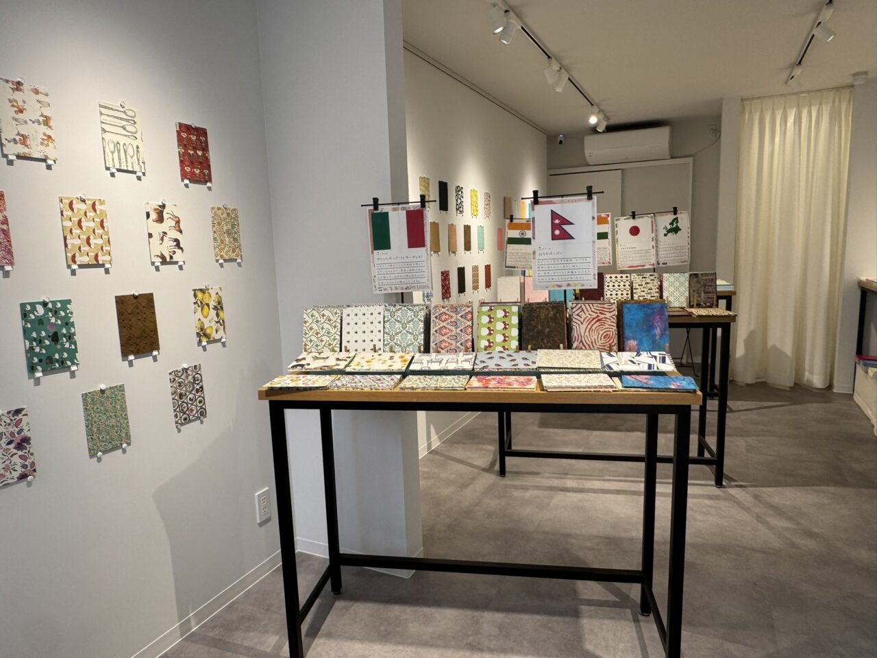ハンコレ吉祥寺店のノートづくりコーナー。壁一面に紙が展示されテーブルに表紙が並ぶ様子