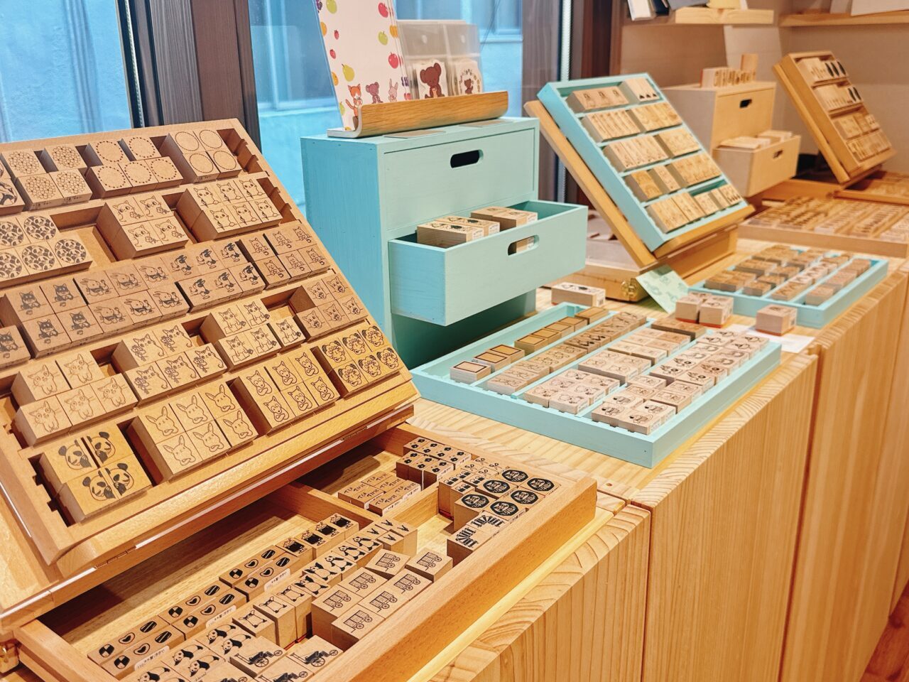 木製の陳列台やパステルブルーの小引き出しにずらりと並べられた動物などの木製ラバースタンプ