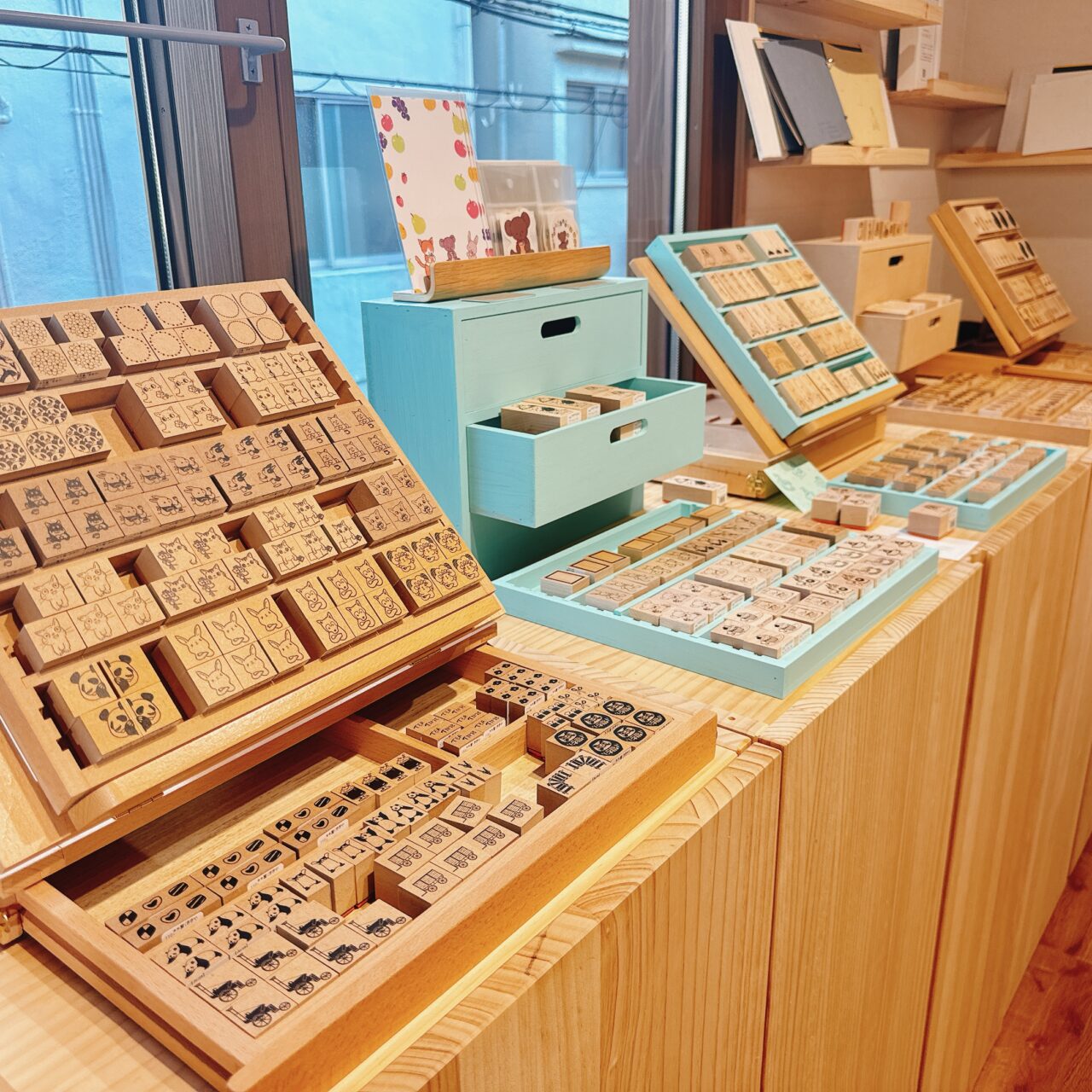 木製の陳列台やパステルブルーの小引き出しにずらりと並べられた動物などの木製ラバースタンプ