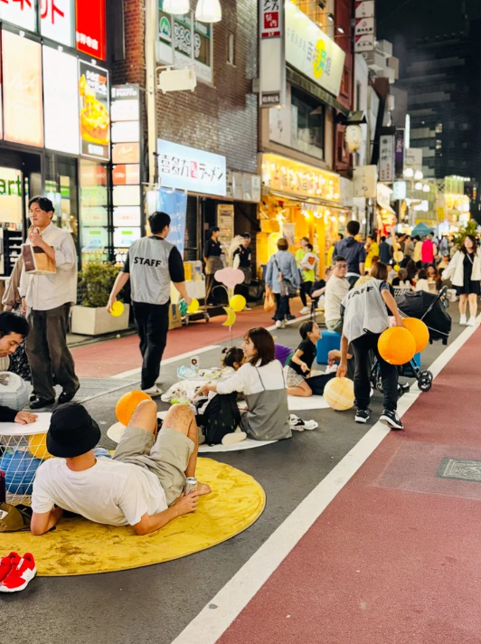 夜間のパークロードが歩行者天国となり路上にシートを敷いてくつろぐ来場者の様子