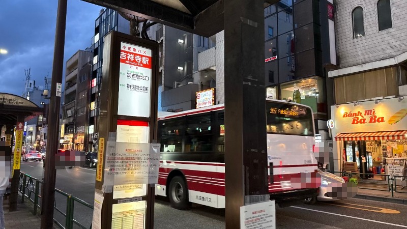 夕方の吉祥寺駅南口バス乗り場の様子。小田急バス車両と運行終了のお知らせが貼られたバス停ポール